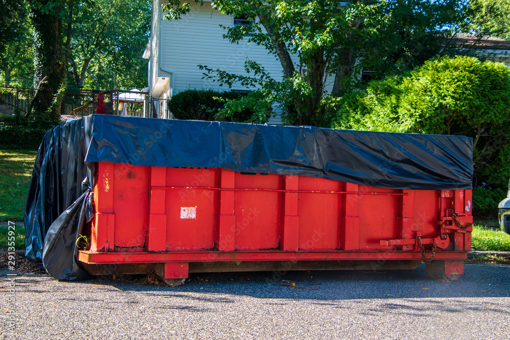 a red dumpster with black tarp on top