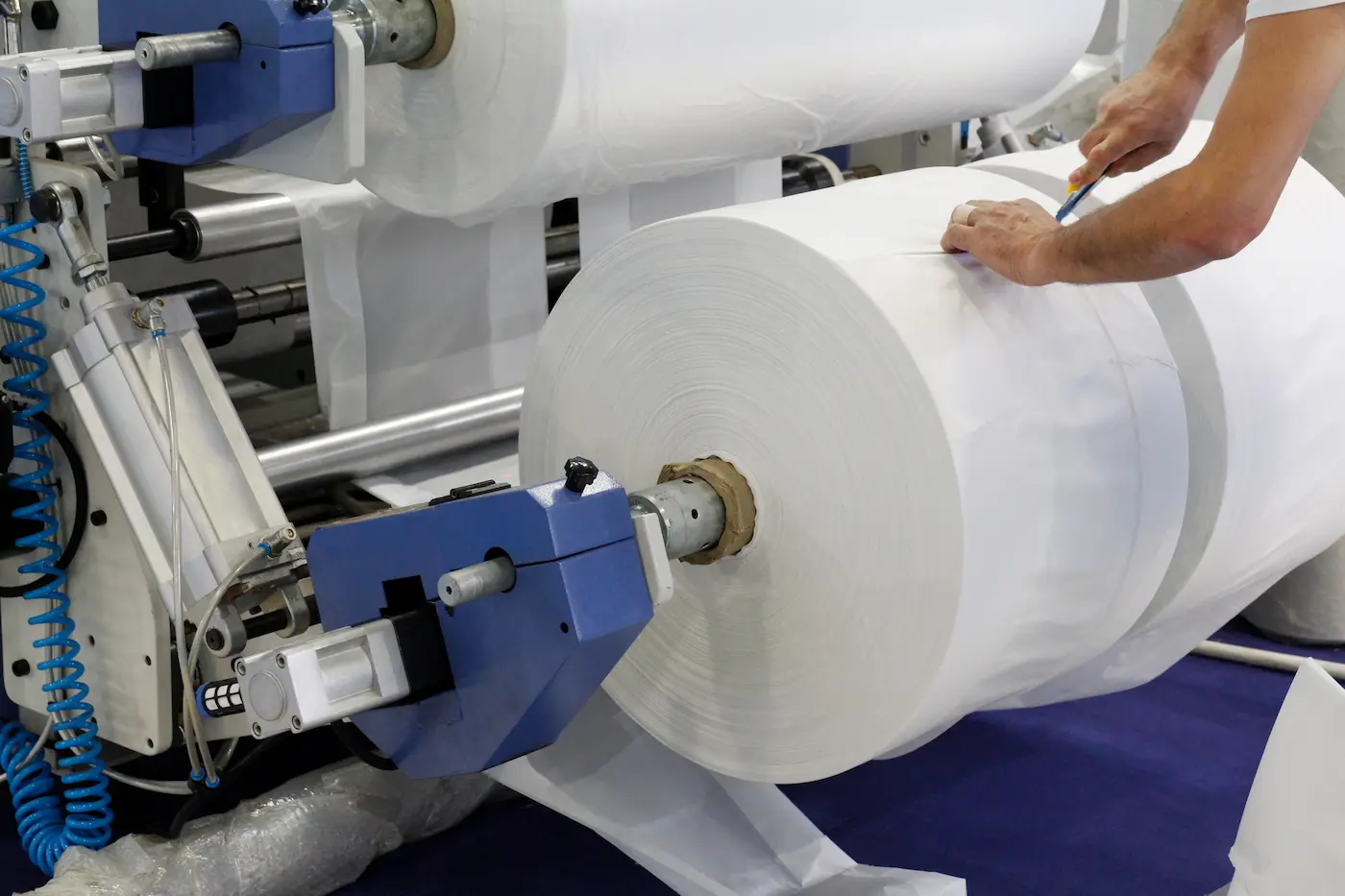 a person using a machine to roll a roll of white plastic