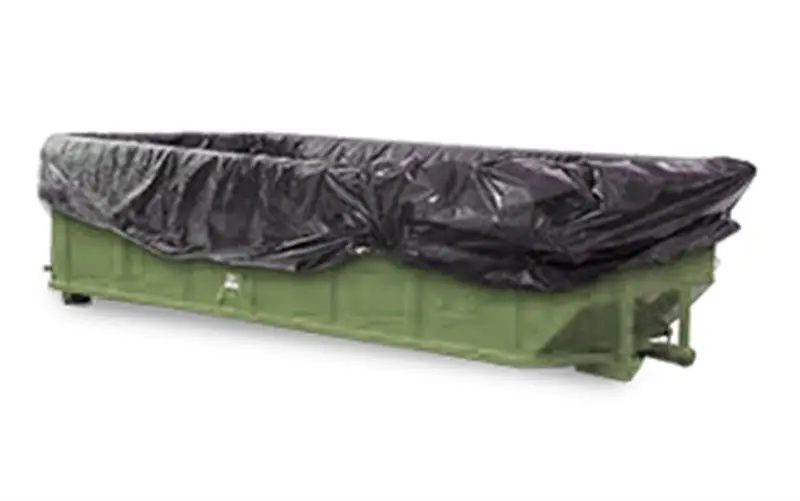 a green dumpster with black plastic bag